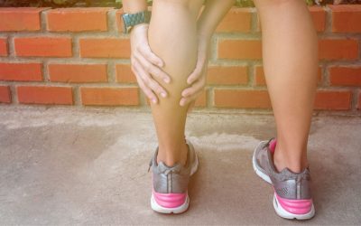Image of a woman holding her calf indicating pain.