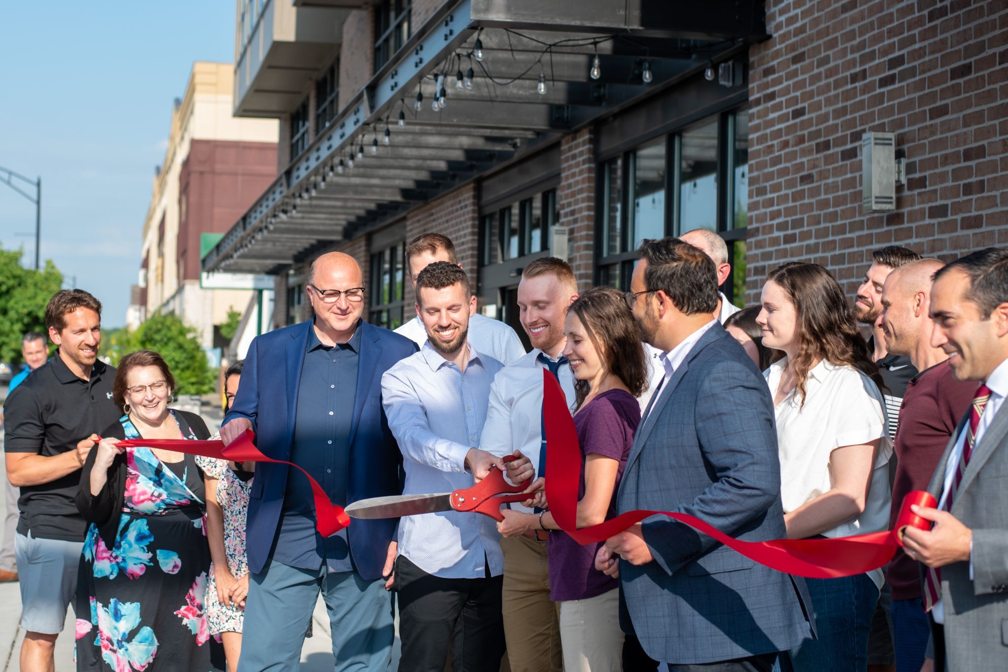 A group of people smile as they cut a ceremonial ribbon.