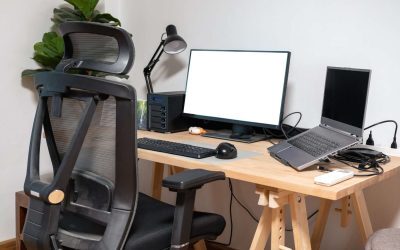 An image of a workspace setup with a monitor and laptop on a desk. There is a black chair in front of it.