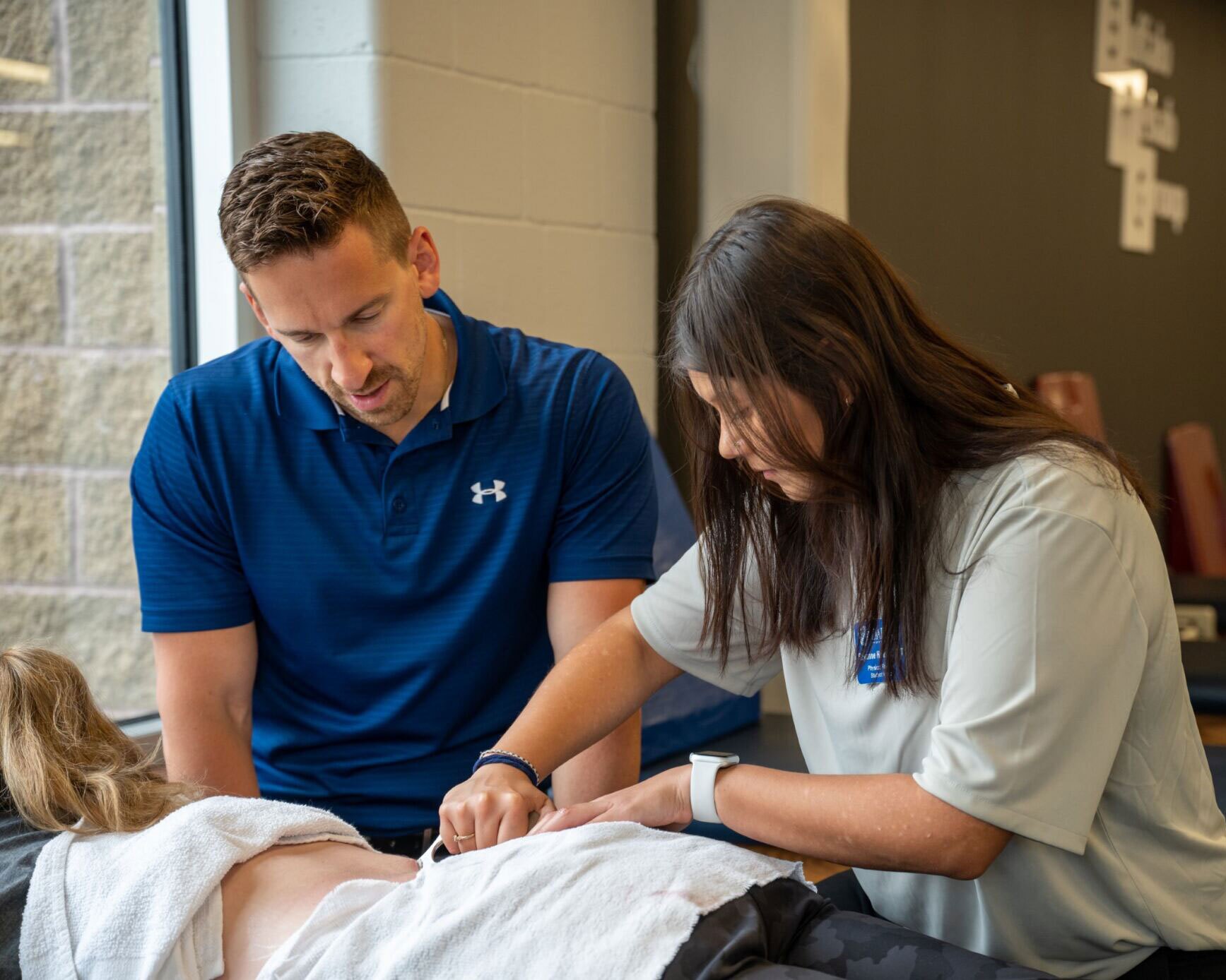 A Physical Therapist helps another PT work on a low back patient.