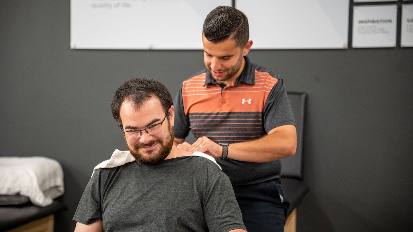 A Physical Therapist happily works on a head & neck patient.