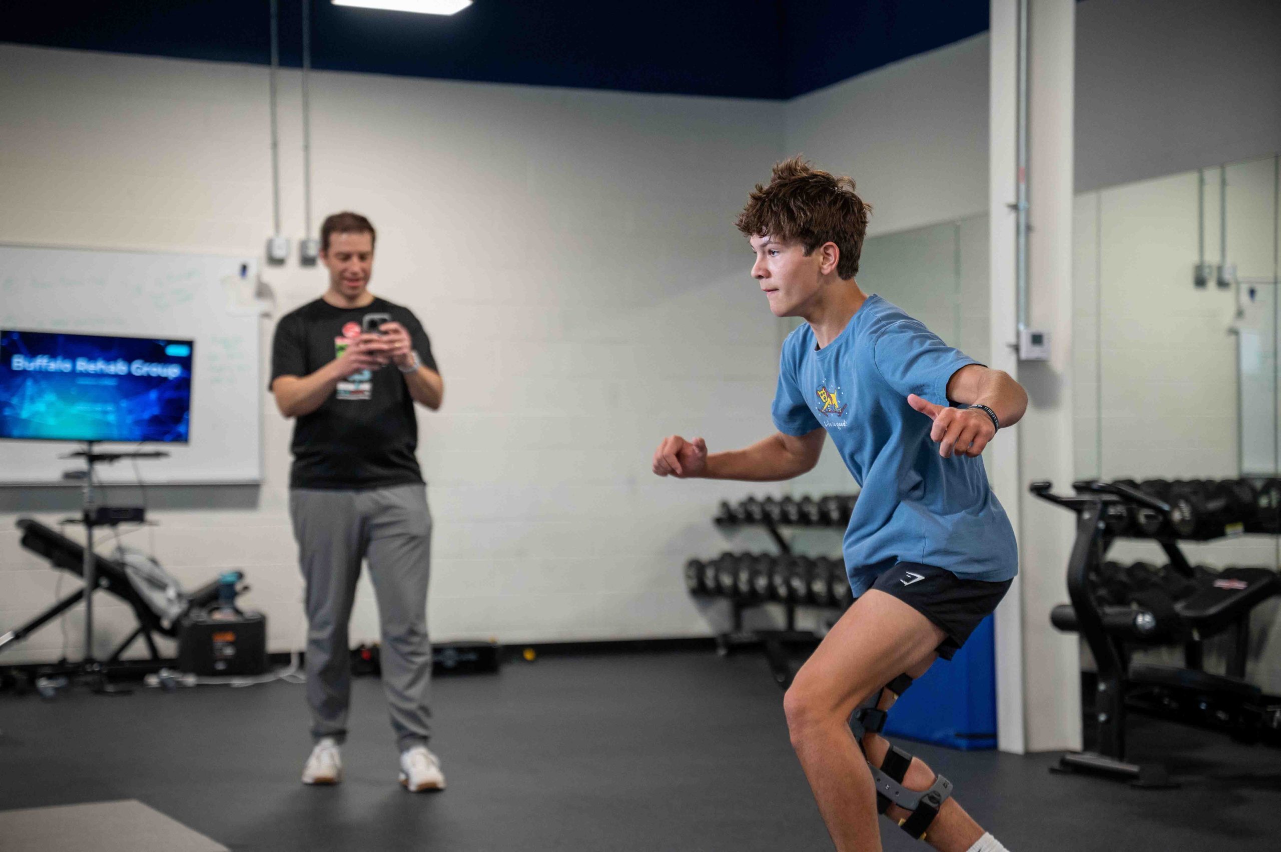 A physical therapist smiles as she converses with her patient.