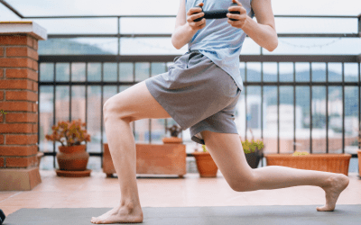 A Caucasian male in gray shorts and a blue t-shirt doing a lunge twist on a yoga mat.